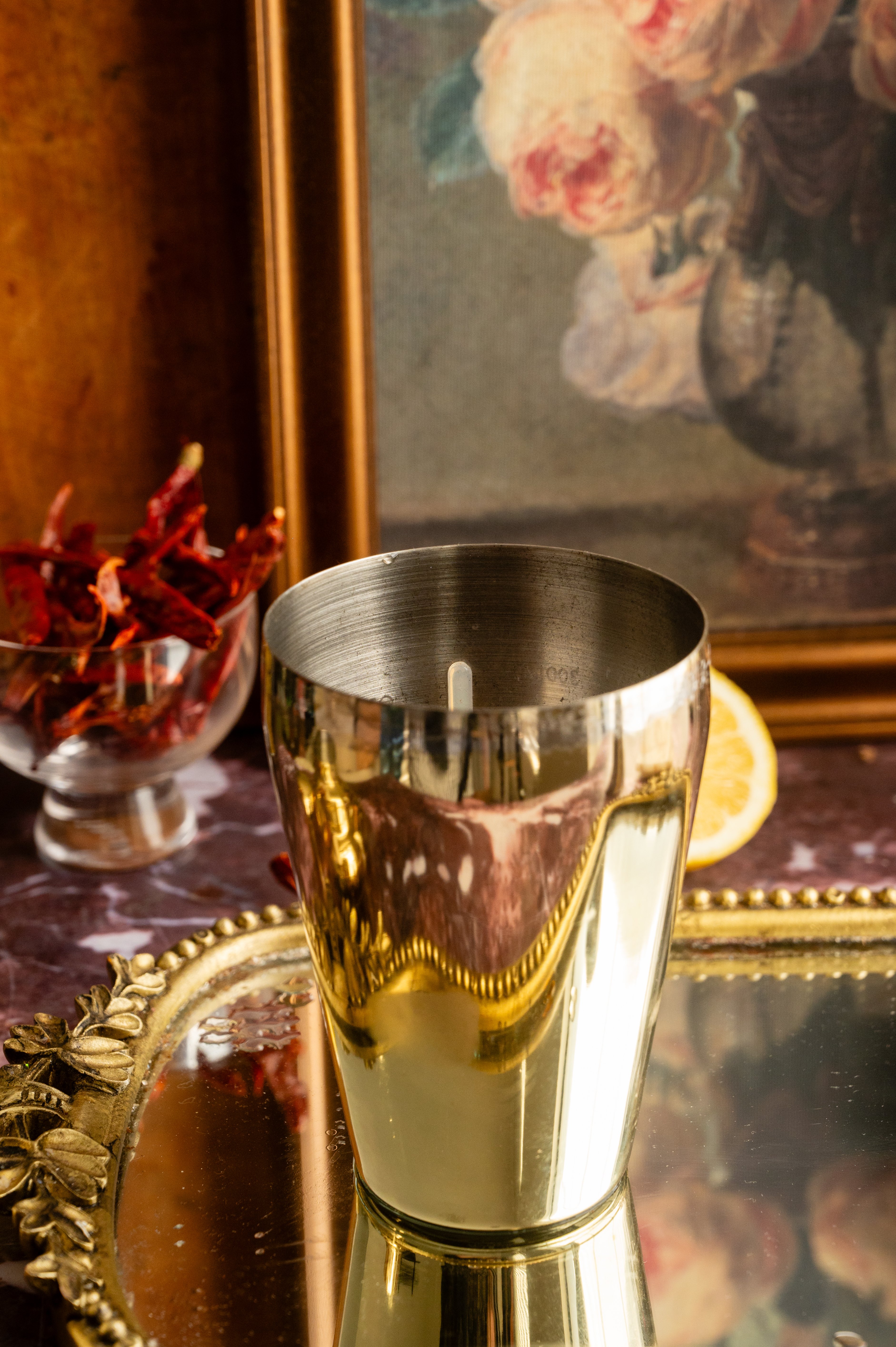 A gold cocktail shaker on the mirrored tray.
