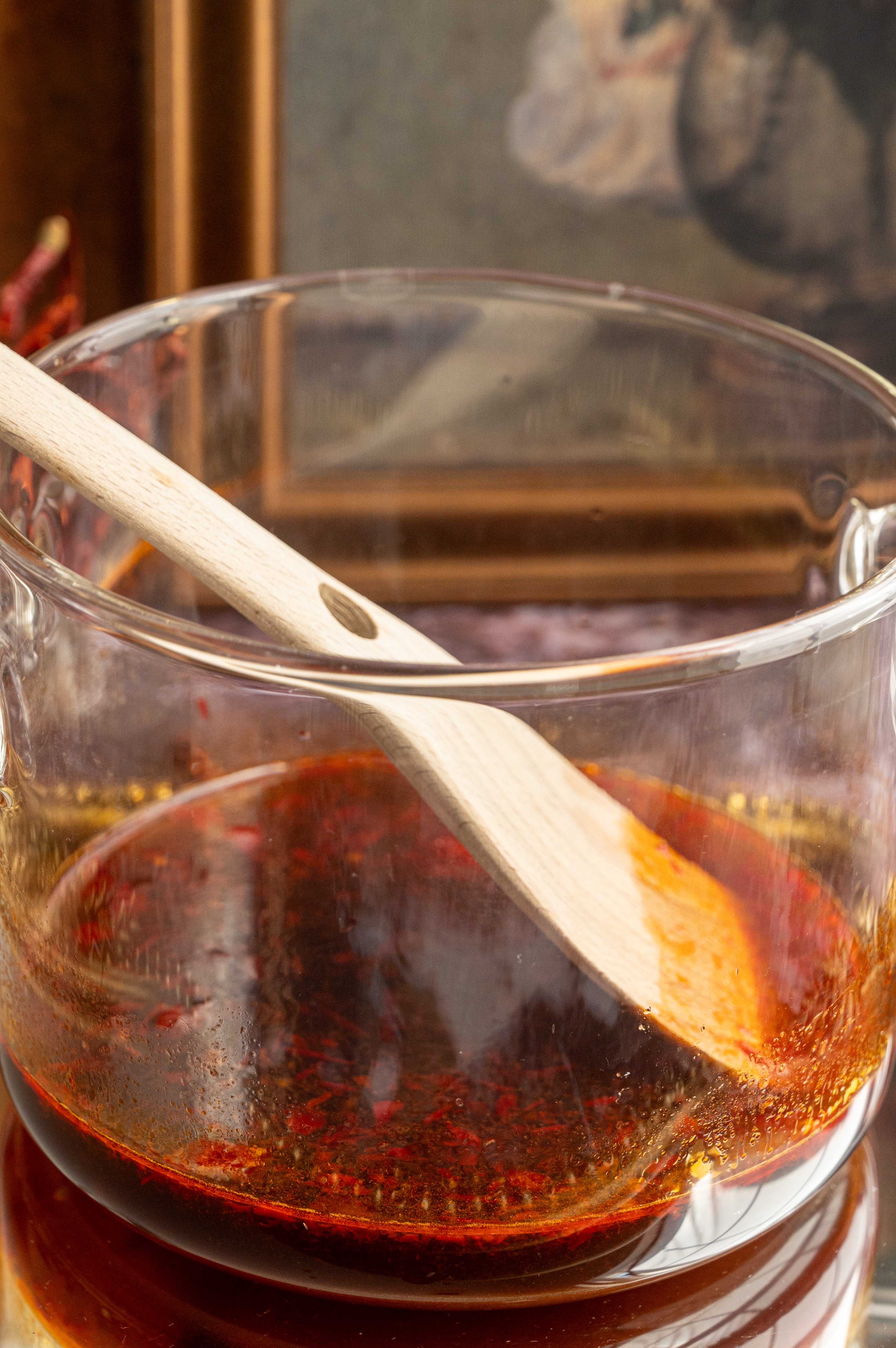 The brown sugar and chili syrup sitting in a glass pot.