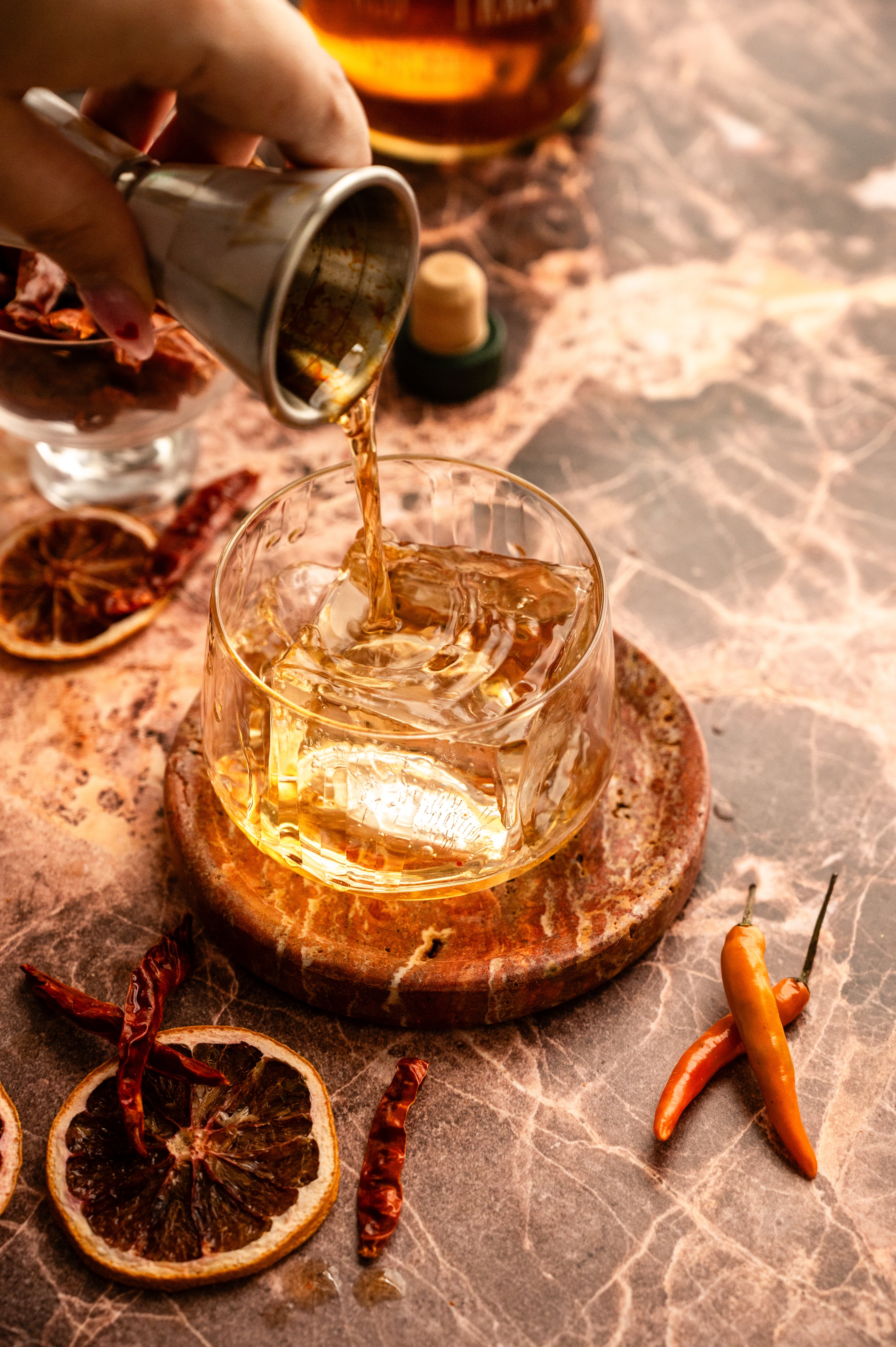 Bourbon being poured into a rocks glass with ice.
