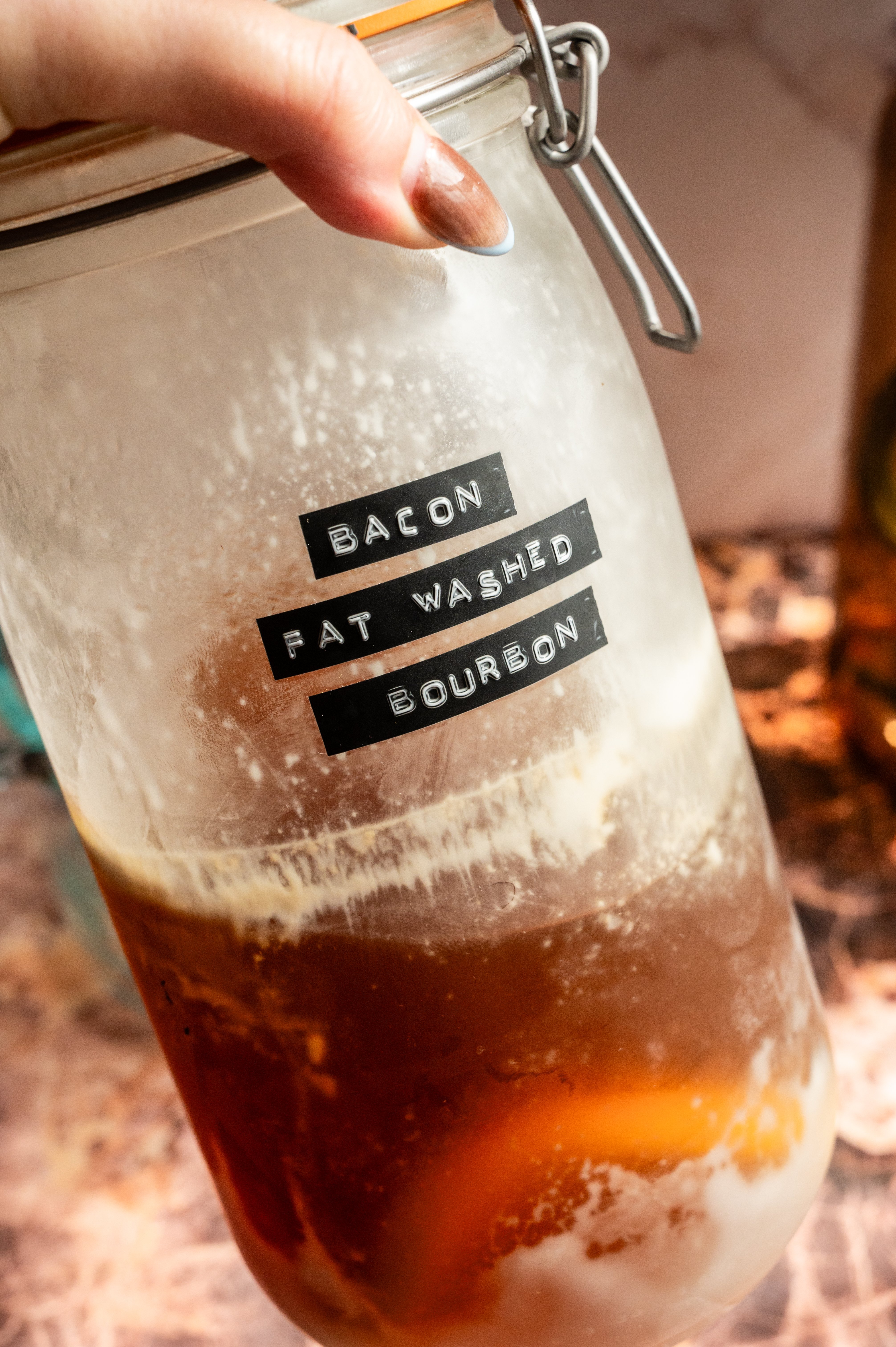 A chilled large glass jar filled with the bacon fat washed bourbon.