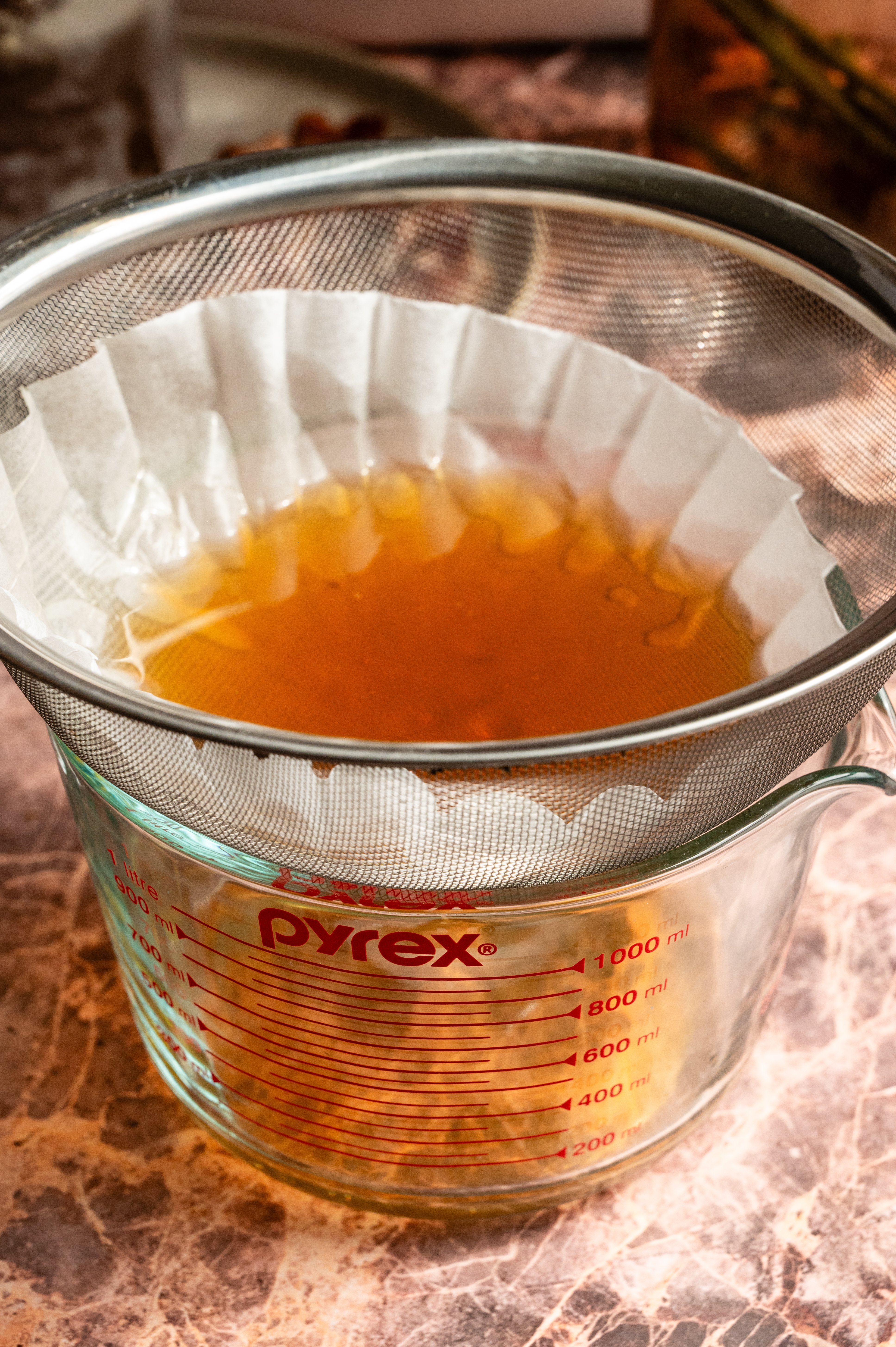 The bourbon is being strained through a coffee filter.