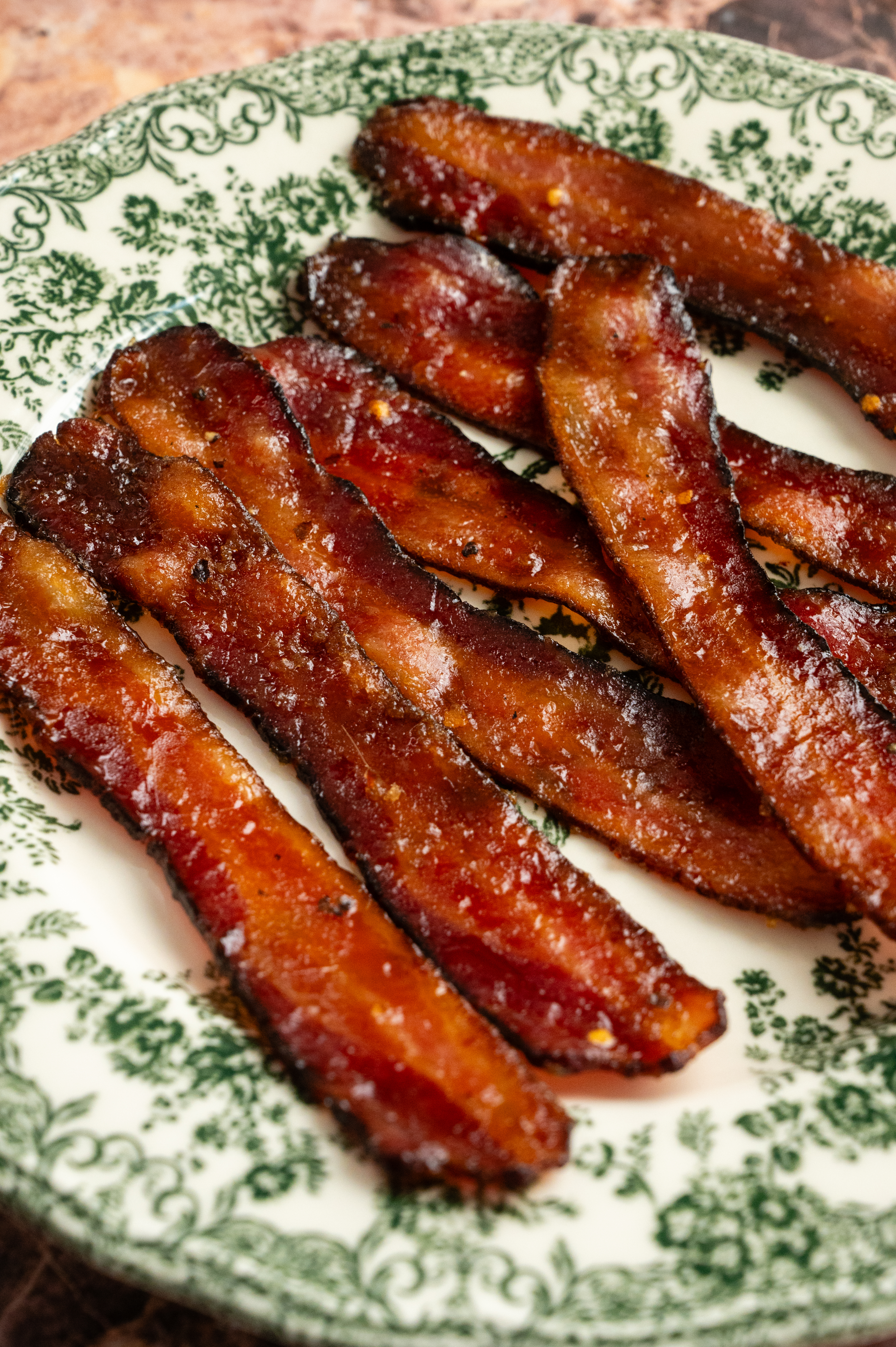 Cooked millionaires bacon on a green and white floral plate.