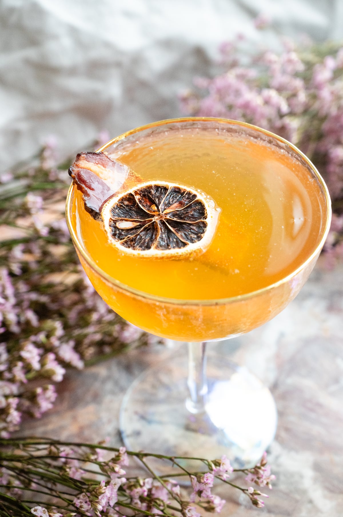 The champagne poured and the drink has been garnished with bacon and lemon.