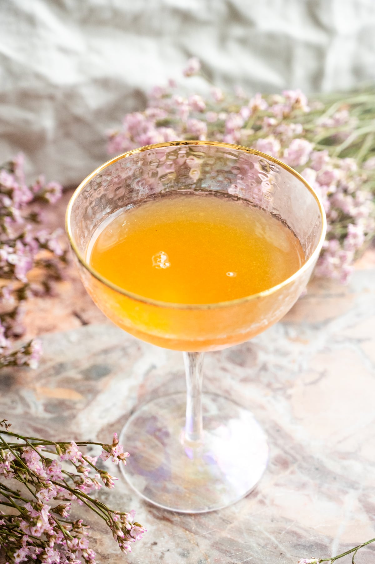 The coupe glass filled with the shaken part of the cocktail.