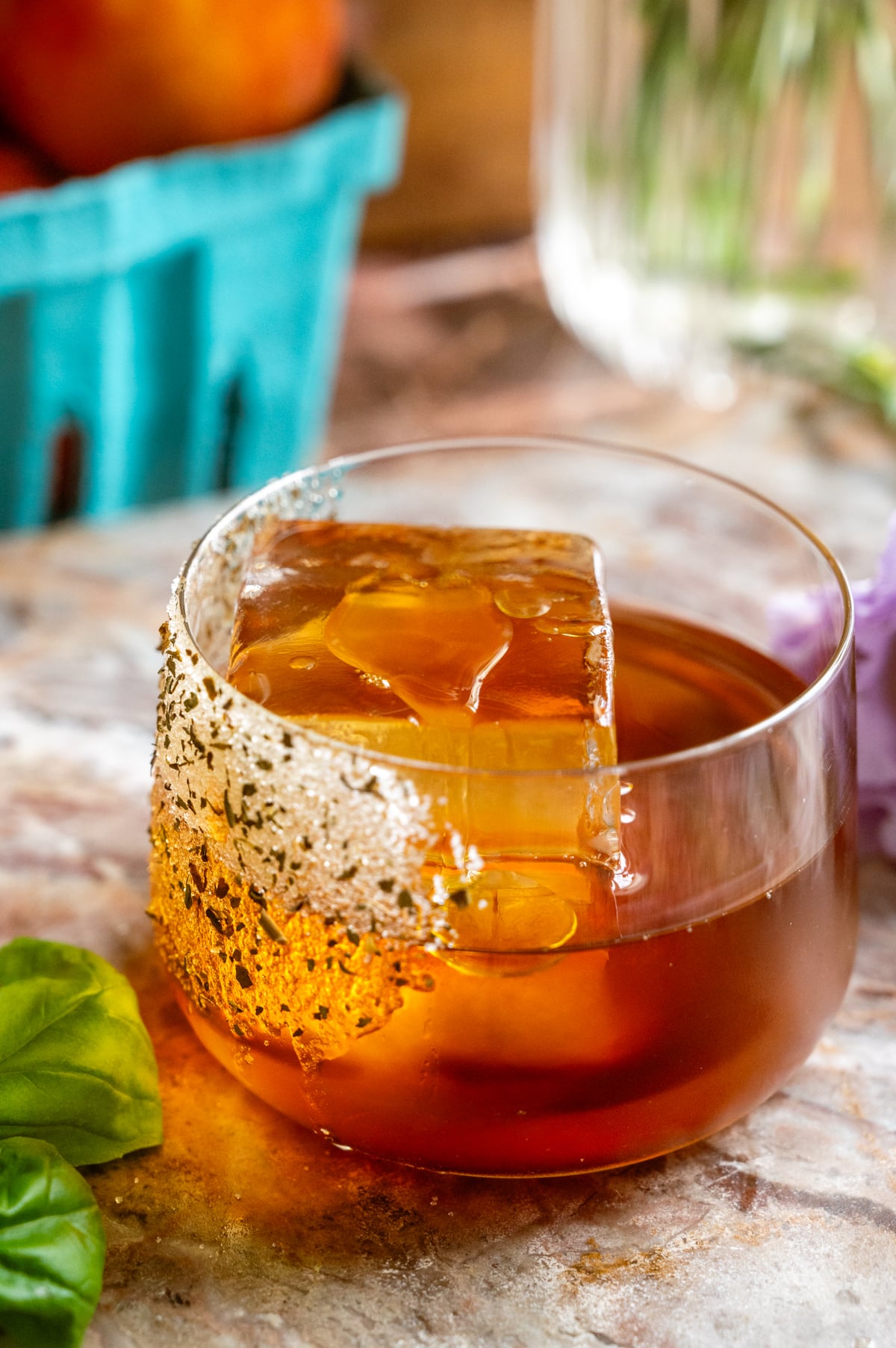 A short rocks glass filled the ingredients and large ice cube. The olive oil is dripping down the side of the ice.