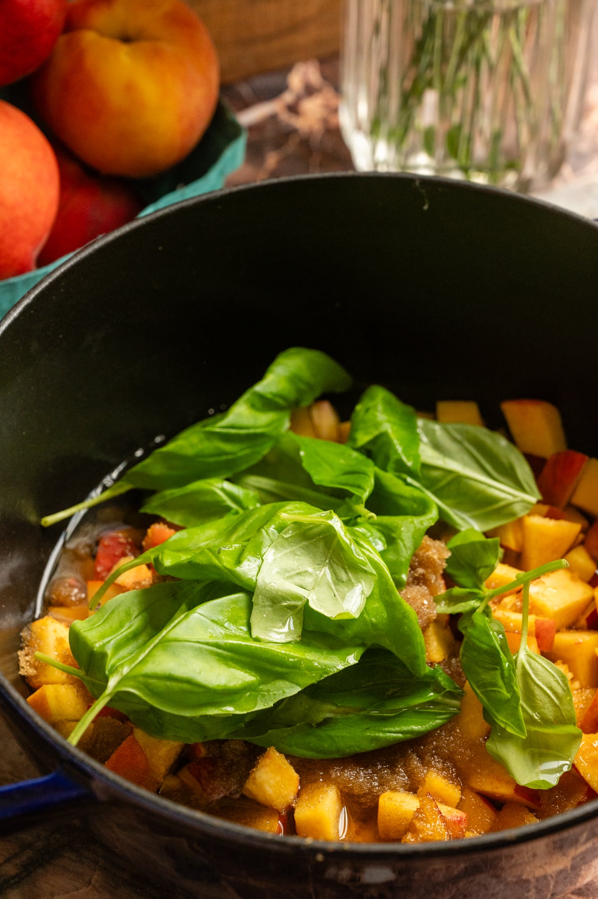 All the ingredients for the peach syrup in a a cast iron pot with the basil sitting on the top.