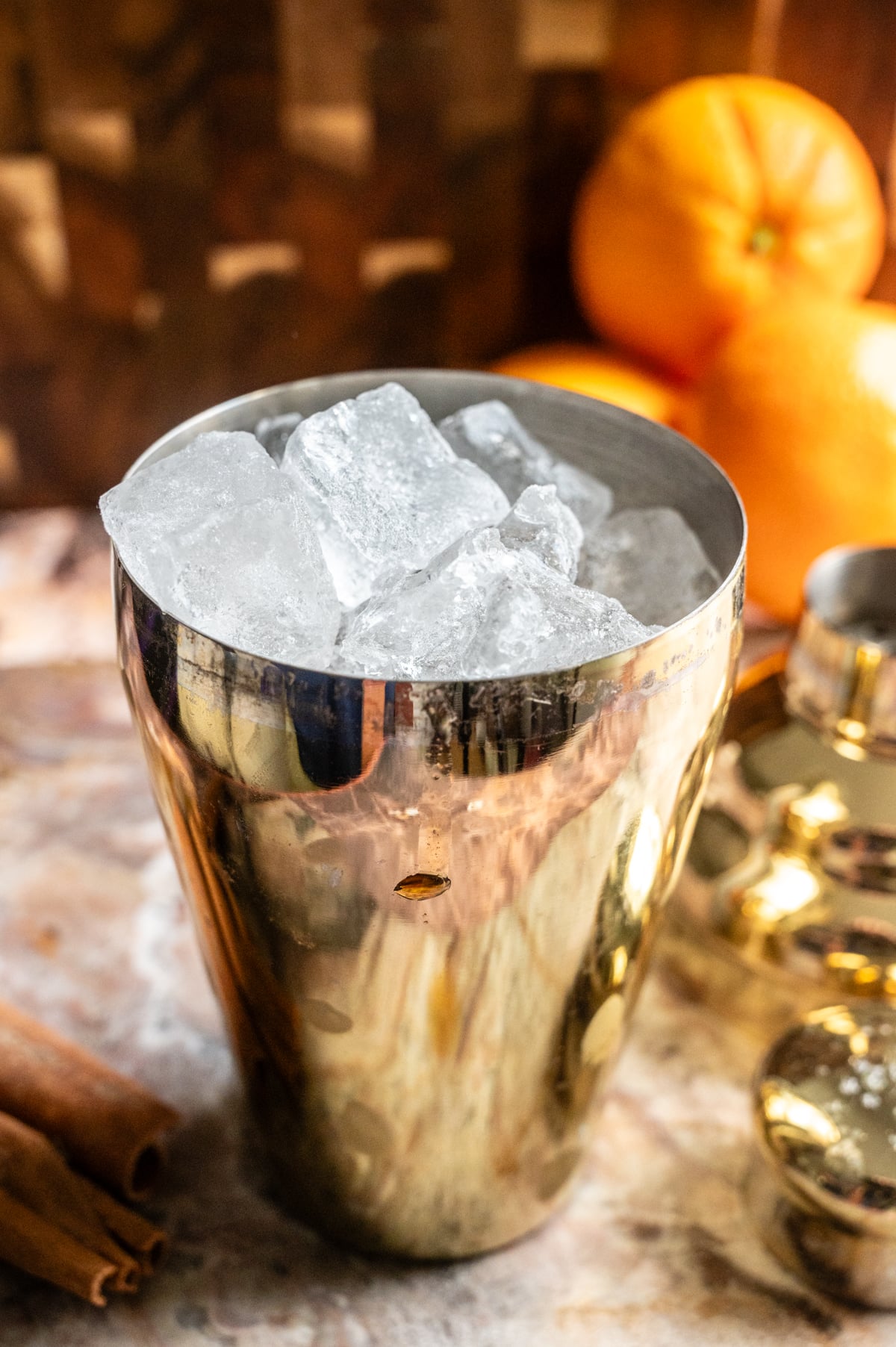 All the ingredients in a gold cocktail shaker and ice is peaking out the top.