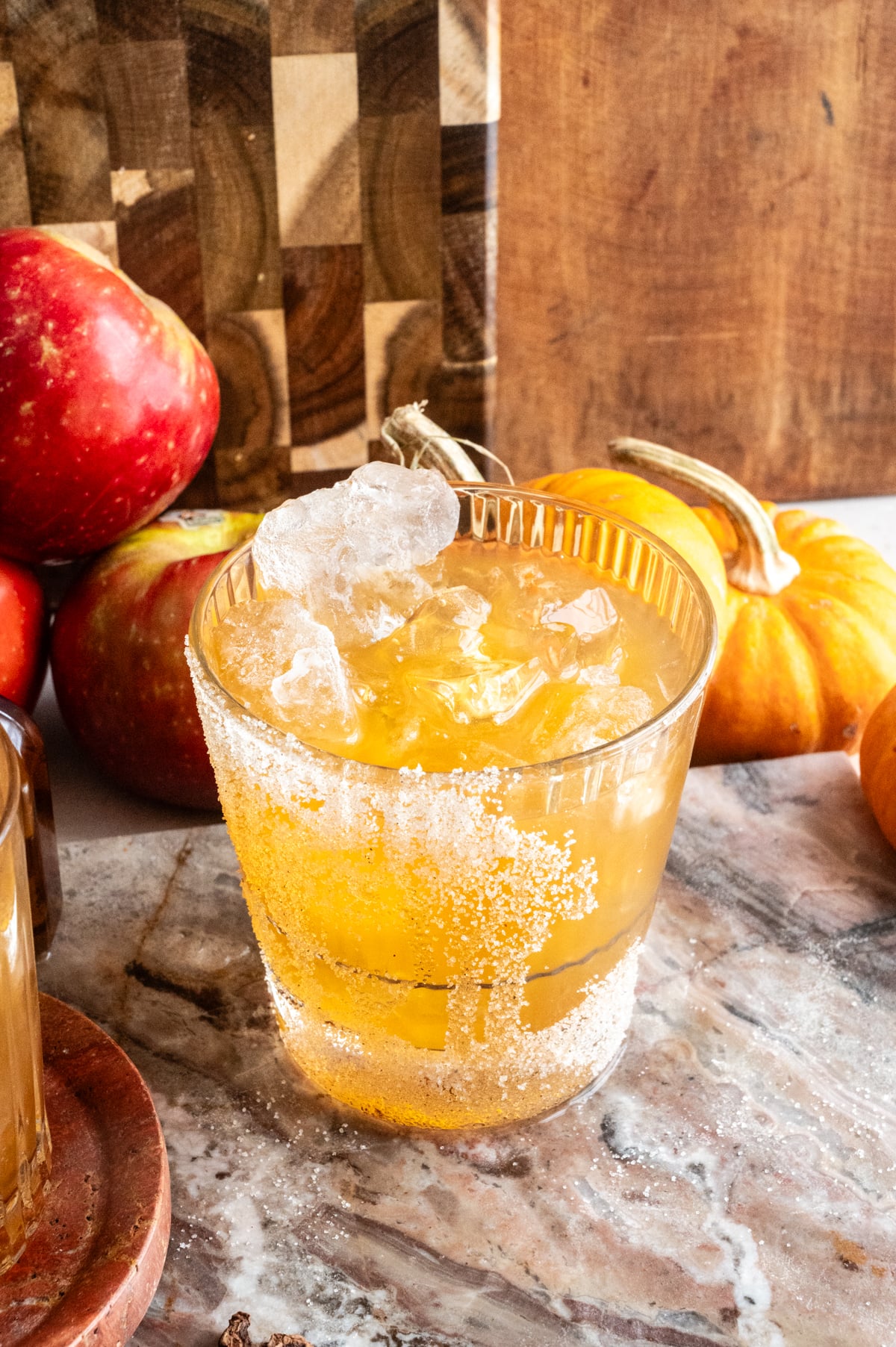 A glass with ice has been filled with apple cider ⅔ of the way.