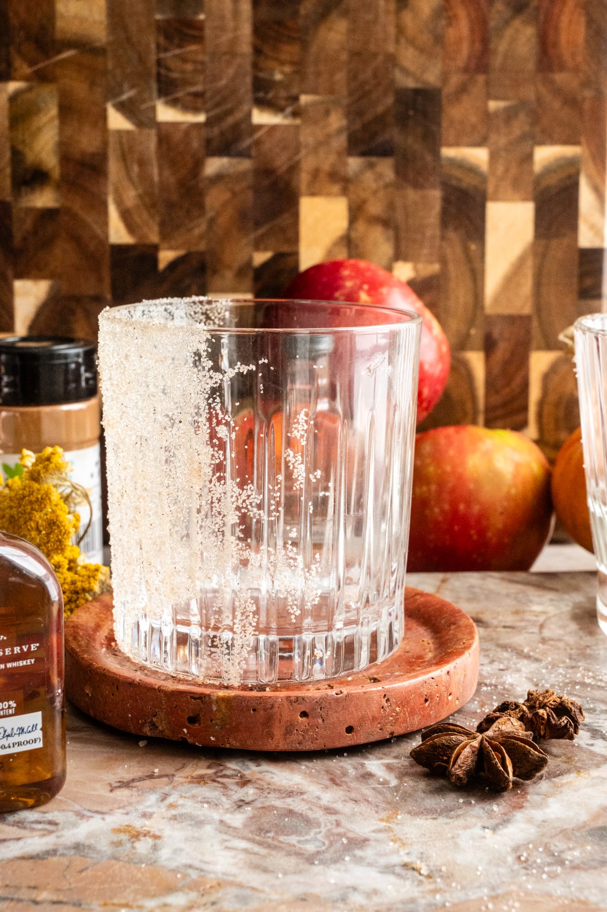 An etched rocks glass with cinnamon sugar covering the side of the glass.