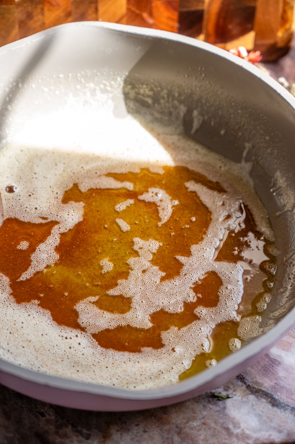 Butter being browed in a light purple skillet.